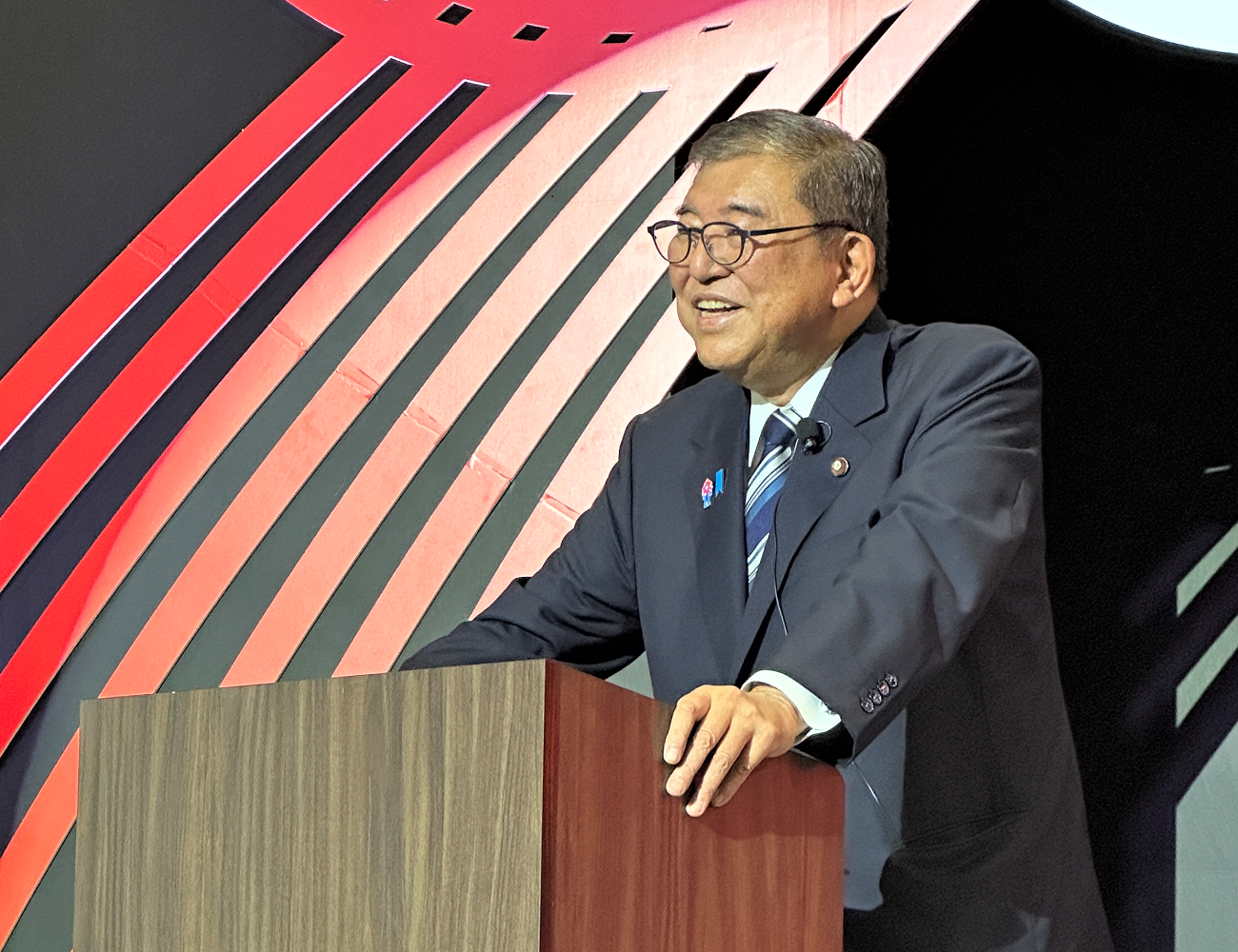 Photo of Prime Minister ISHIBA delivering an address with a warm smile during the closing session