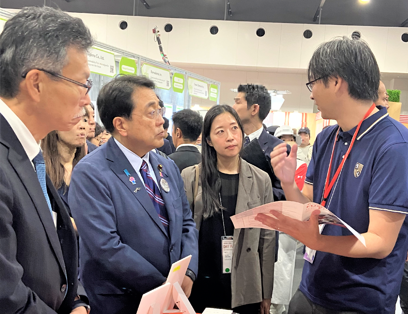 Photo of Minister AKAZAWA, Minister in charge of Startups and Dr. YUMITORI Shuji, Executive Director of NEDO engaging with a startup’s presentation at the booth